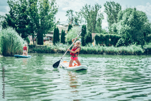 brave child on paddle board having fun and adrenaline on pond photo