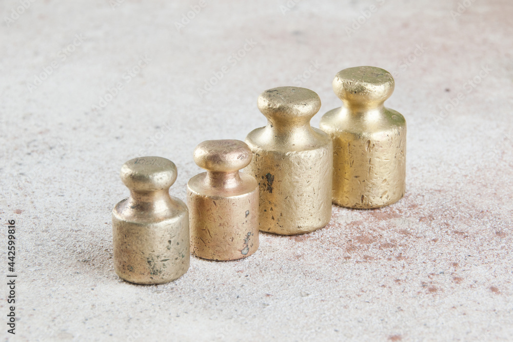 Four antique bronze weights for scales on concrete background. Four antique bronze weights for scales on concrete background.