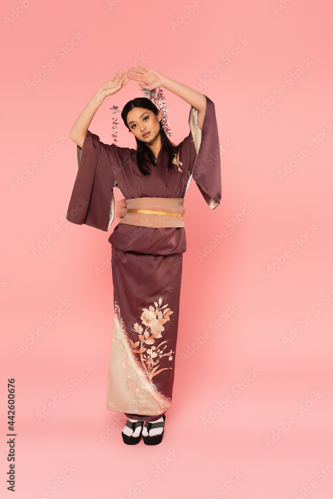 Full length of asian woman in oriental footwear and kimono on pink background