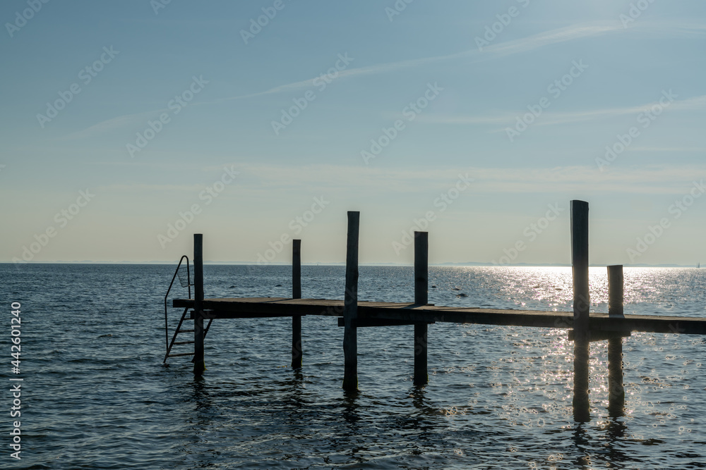 sunset over the ocean with a wooden dock and ladder for swimming in the foreground