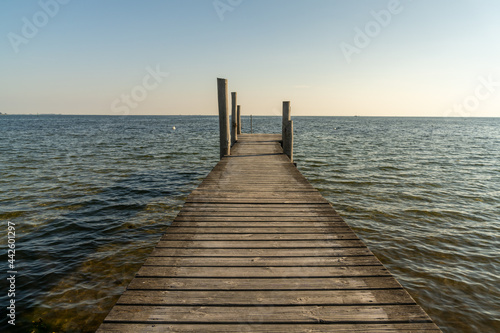 wooden dock leading out into a calm blue ocean in evening light