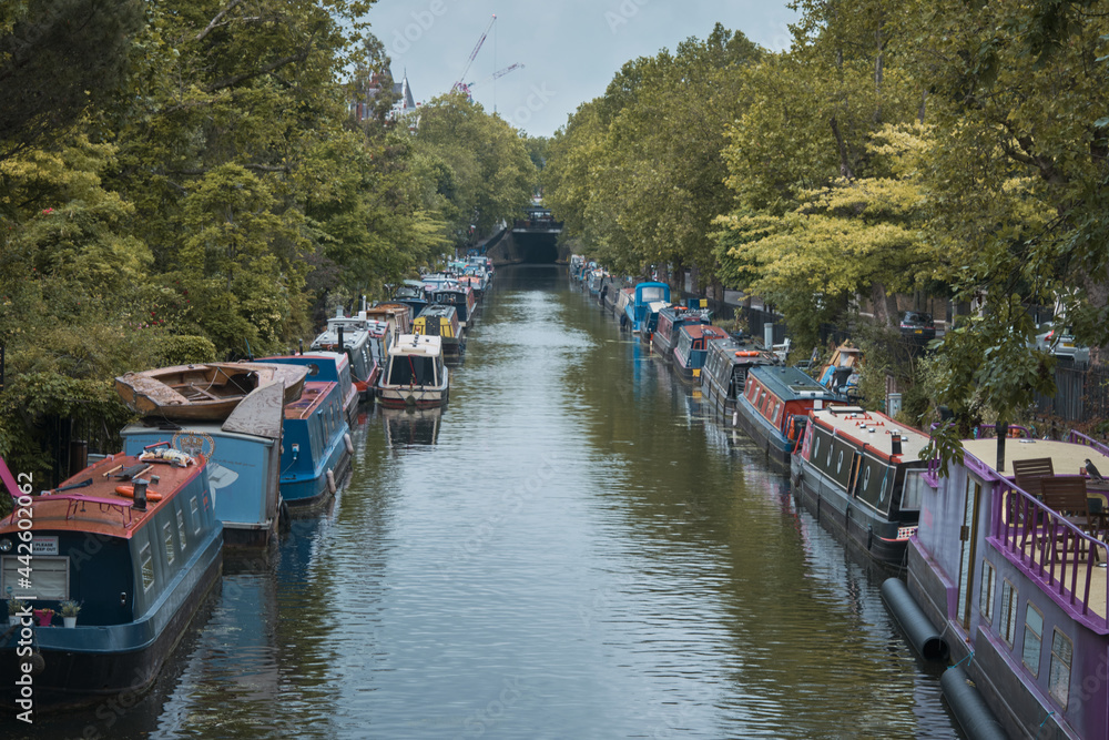 Rows of houseboats and narrow boats on the Regent's canal on Maida Avenue, Little Venice, West London, on a bright fall day. Rows of houseboats and narrow boats on the Regent's canal on Maida Avenue, Little Venice, West London, on a bright fall day.