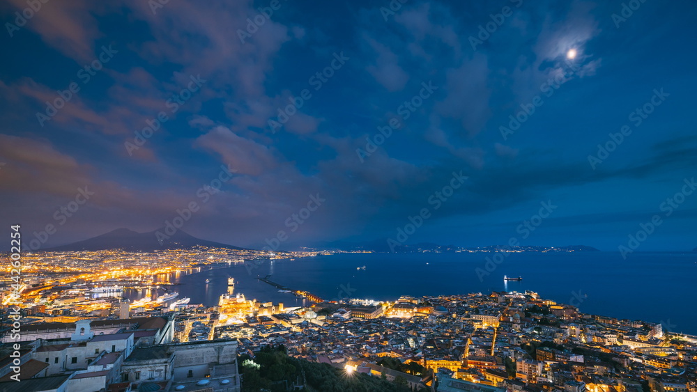 Naples, Italy. Top View Skyline Cityscape In Evening Lighting. Tyrrhenian Sea And Landscape With Volcano Mount Vesuvius. City During Sunset And Night Illuminations. Day To Night Transition