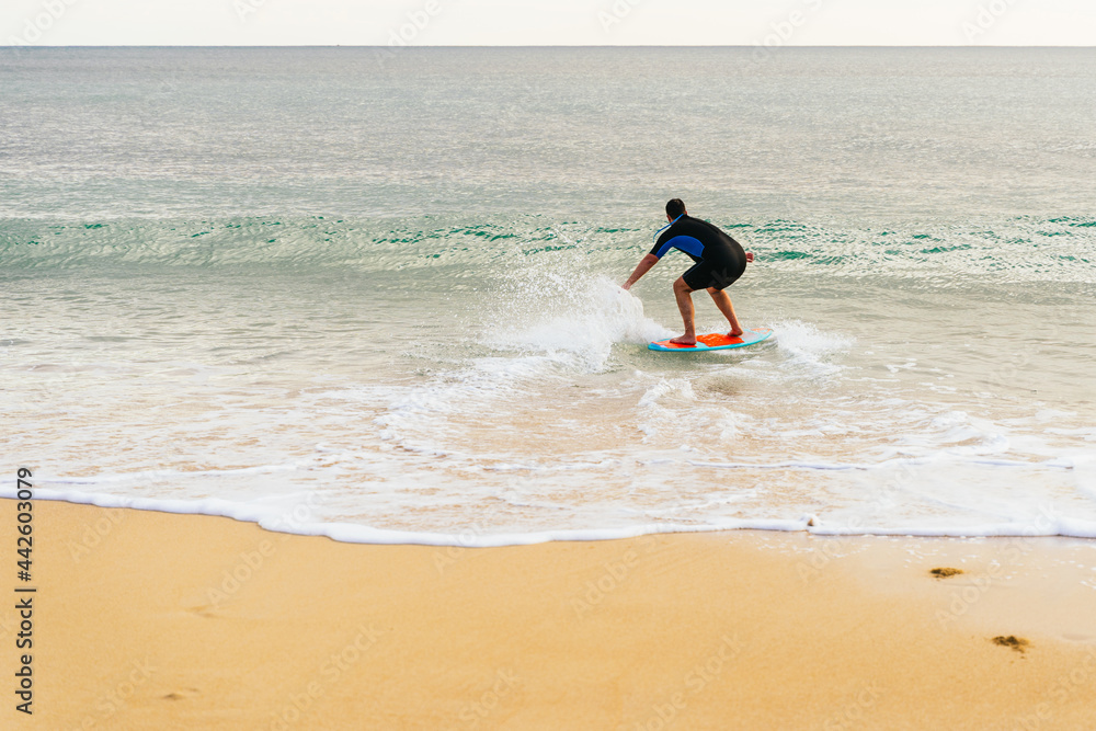 Caucasian hispanic man surfing on a skimboard at sunset on the beach Caucasian hispanic man surfing on a skimboard at sunset on the beach
