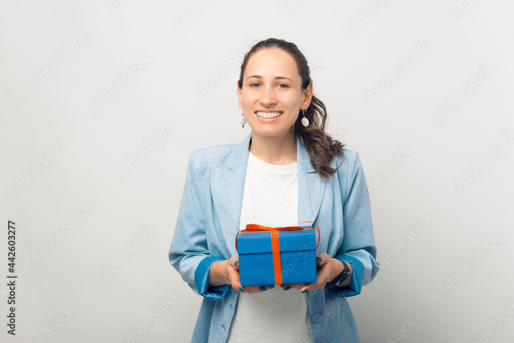 Portrait of young smiling woman in casual holding blue gift box over white background Portrait of young smiling woman in casual holding blue gift box over white background