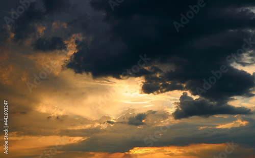 beautiful sunset sky  bright sun and dark silhouette of clouds as a background