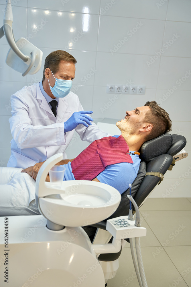 Obraz premium Professional dental surgeon conducting medical check-up for young man