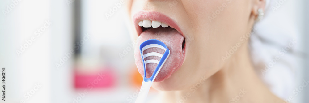 Woman cleans her tongue with special scraper - obrazy, fototapety, plakaty 