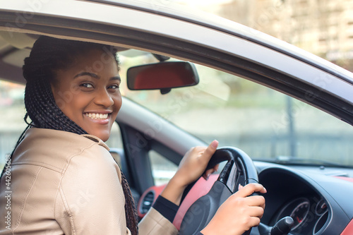 happy african-american woman in a car driving, autumn-winter