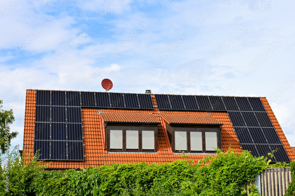 Fototapeta premium Solarzellen auf rotem Hausdach zur Erzeugung von grünem Strom