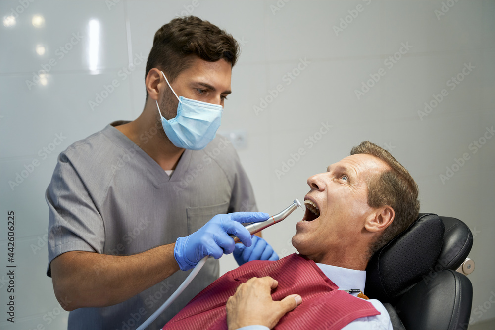 Fototapeta premium Certified dentist treating his patient at the clinic