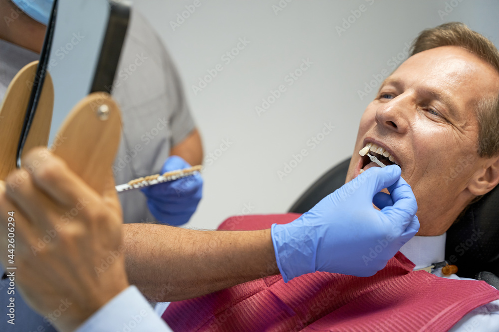 Fragment photo of middle-aged man doing teeth-whitening in clinic Fragment photo of middle-aged man doing teeth-whitening in clinic