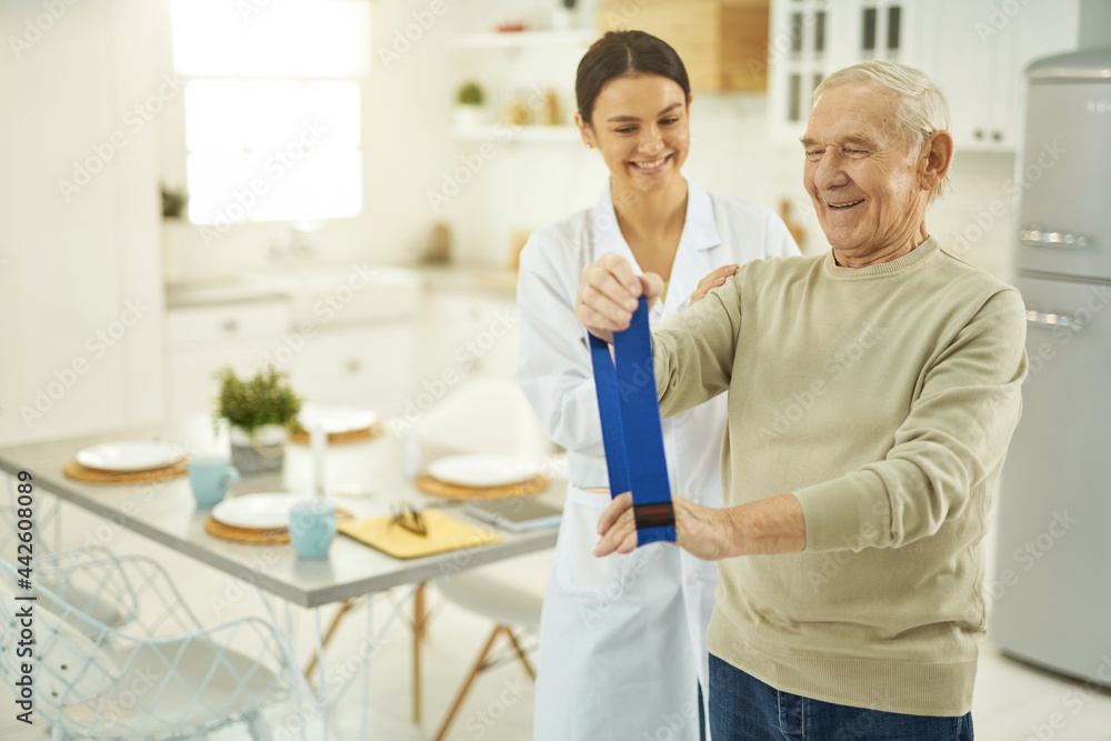 Fototapeta premium Pensioner and young nurse looking at fitness rubber
