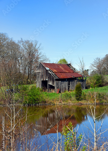 Barn and Sky Reflect in Still Water of Farm Pond
