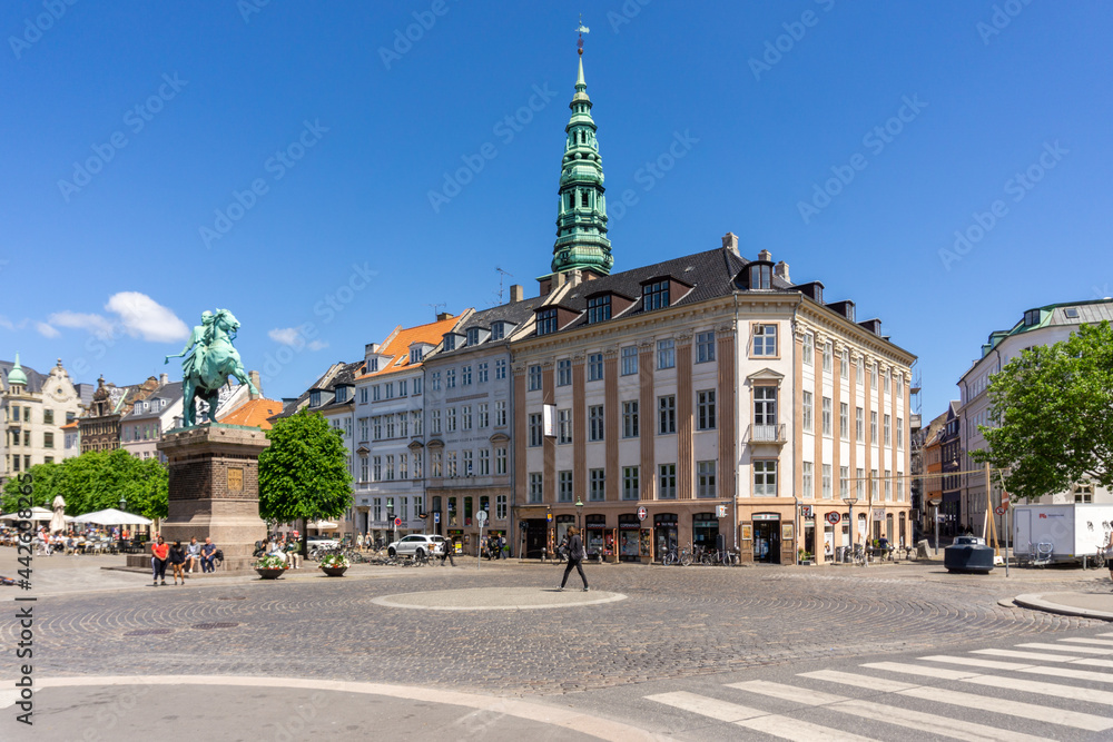 busy city street in downtown Copenhagen on a beautiful summer day with the Danish king's statue in the center