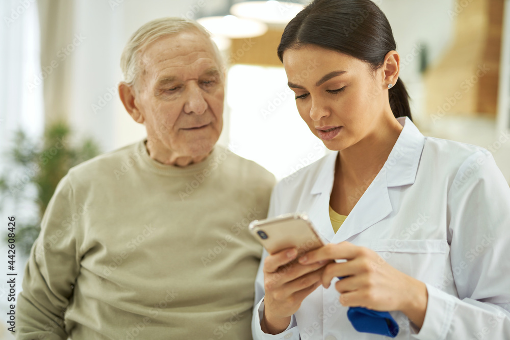 Nurse and senior citizen looking at mobile phone screen Nurse and senior citizen looking at mobile phone screen