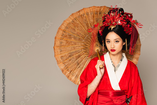 Obraz na plátně Japanese woman with red lips holding umbrella isolated on grey
