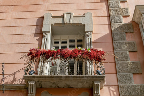 Detailed view on front facade window and small balcony with decorative flowers. Coral and grey house facade in downtown of Cartagena. Details of buildings and city architecture concept.