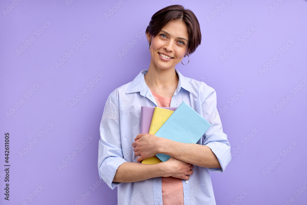 beautiful woman with short hair holding books in hands, smiling at camera, wearing casual outfit. learning, studying, education, university concept beautiful woman with short hair holding books in hands, smiling at camera, wearing casual outfit. learning, studying, education, university concept