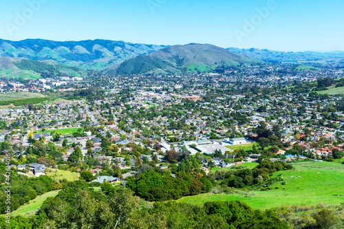 Elevated scenic view of San Luis Obispo urban area sprawl and green mountains of Santa Lucia Range from Bishop Peak Trail on sunny spring day photo
