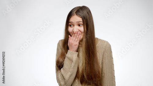 Portrait of girl closing her mouth while scoffing or mocking of someone. photo