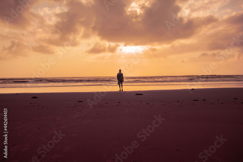 person walking on the beach at sunrise