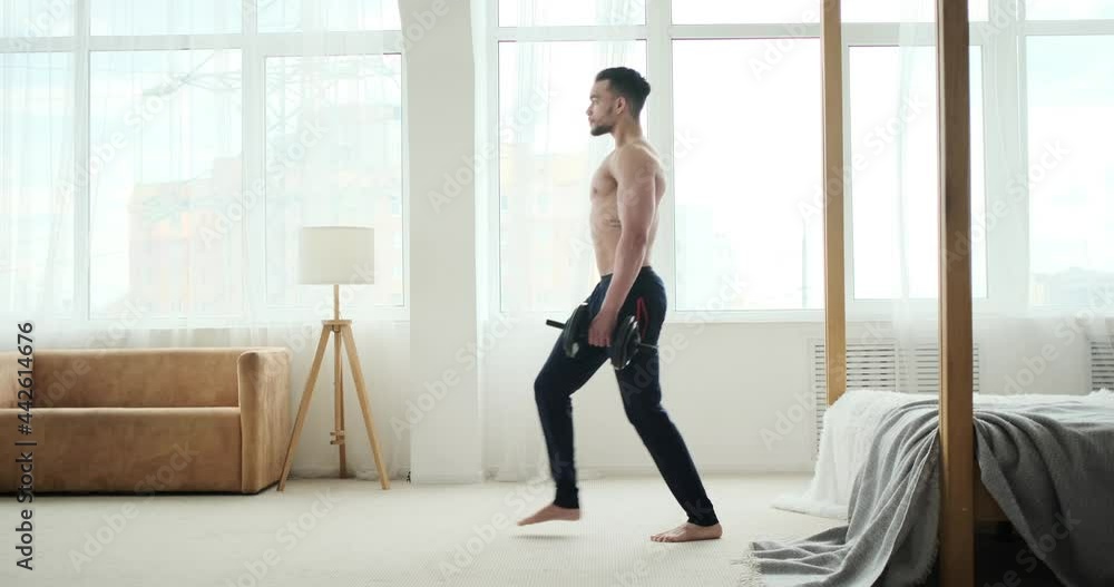Young man doing lunges exercise with dumbbells at home Young man doing lunges exercise with dumbbells at home