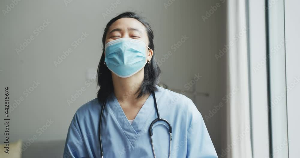 Portrait of happy asian female nurse wearing face mask holding tablet in hospital, smiling to camera Portrait of happy asian female nurse wearing face mask holding tablet in hospital, smiling to camera