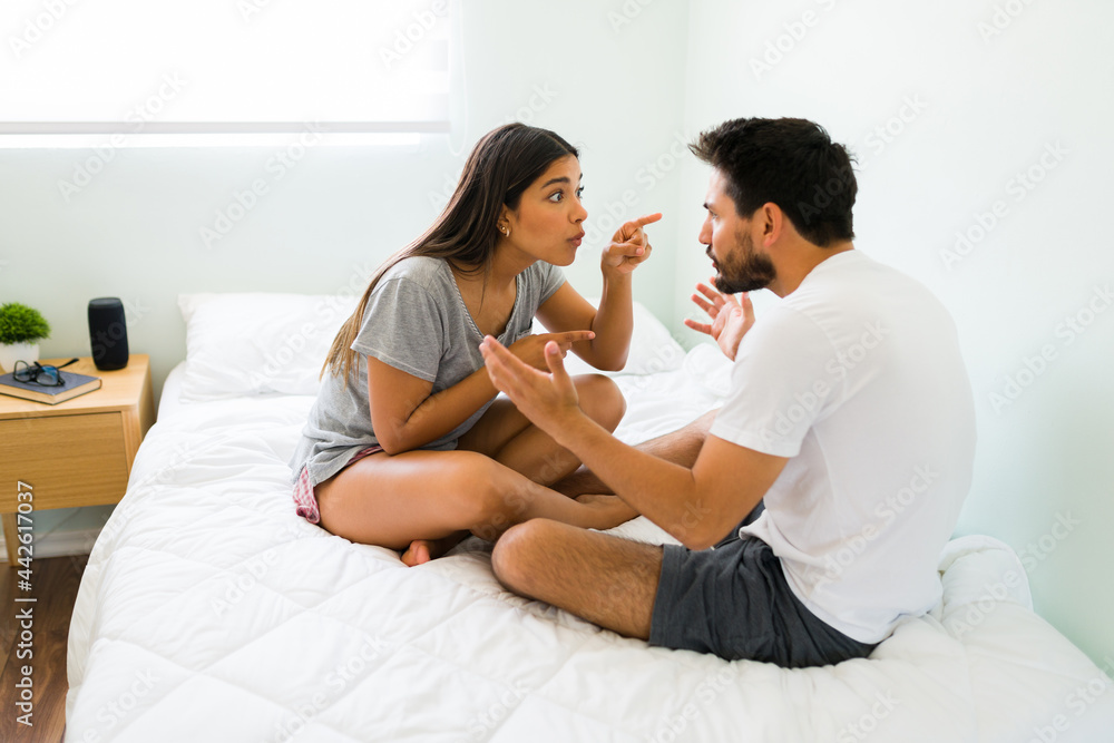 Angry couple in pjs having a fight in bed Angry couple in pjs having a fight in bed