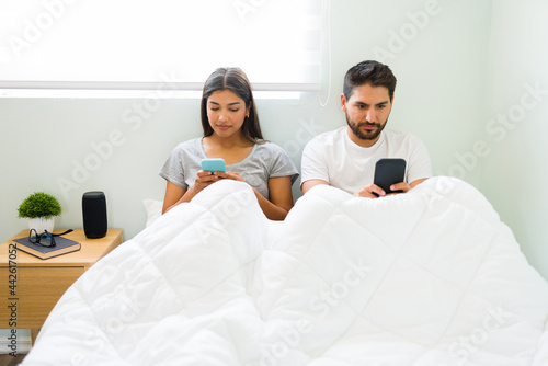Girlfriend and boyfriend using their phones in the bedroom