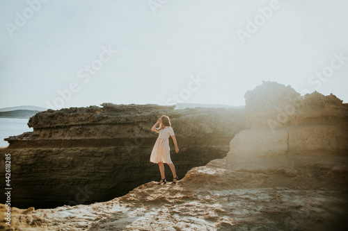 Faceless woman standing on rocky seacoast