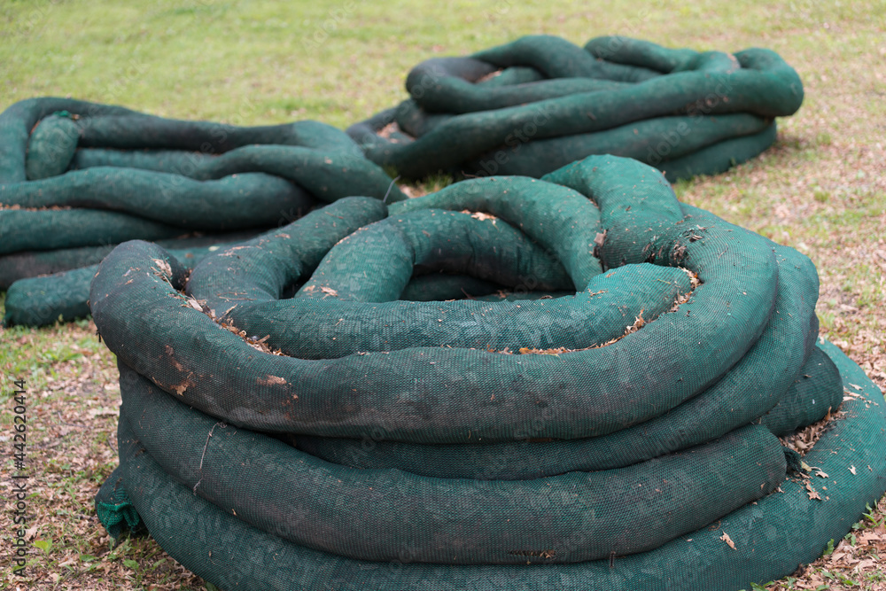 Ταπετσαρία coiled dark green silt socks (filled with wood chips) on grass