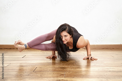 Mujer hispana realizando posturas de yoga, en fondo blanco