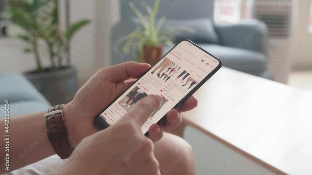 Close Up Of Man Hand Holding Smartphone And Doing Online Shopping At Home, Male Looks At Goods In Online Store Clothing
