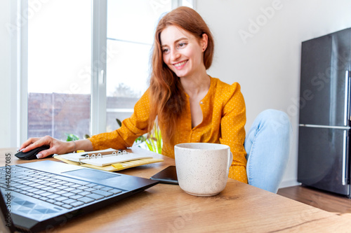 Defocus. Young woman is education online by using computer. Female freelancer browsing laptop.