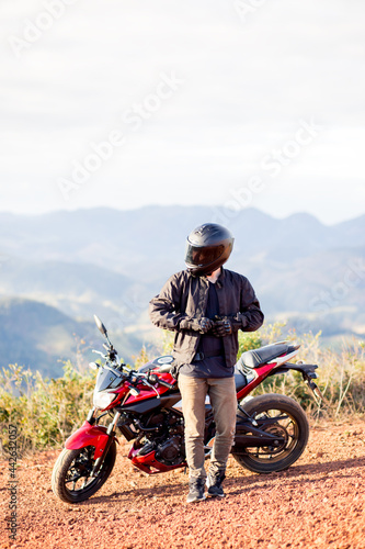 Young man standing on the side of his motorbike. Concept of freedom and enjoying the journey.