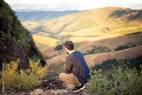 Young man on the edge of a cliff observing the landscape.