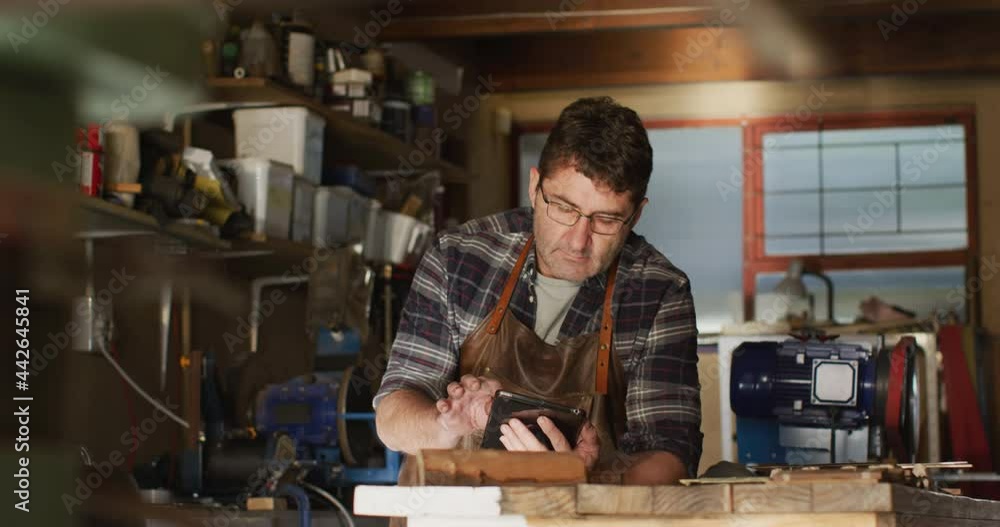 Focused caucasian male knife maker in workshop using tablet Focused caucasian male knife maker in workshop using tablet