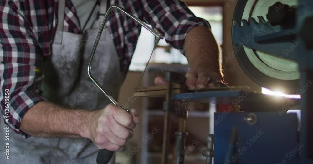 Midsection of caucasian male knife maker in workshop using saw Midsection of caucasian male knife maker in workshop using saw