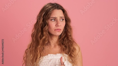 An excited woman fingering her fingers and grabbing her head in a pink studio