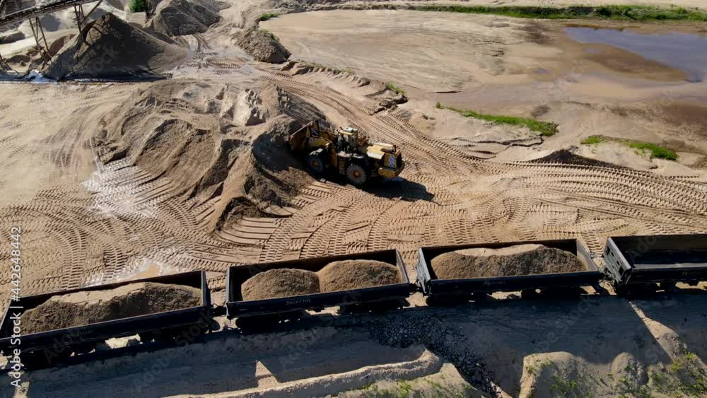 Wheel loader loading sand it to the freight train. Mining work in open ...