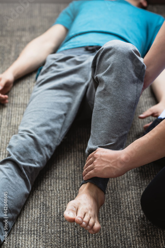 Close-up of a man physiotherapist stretching a patient at a clinic.