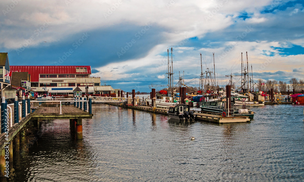 Promenade in the village of Steveston, summer grounds of restaurants and fishermen marina  at waterfront of Richmond City on a background of stormy sky