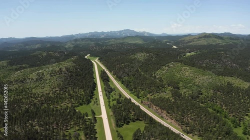 Aerial above forest and roads heading to Mount Rushmore National Memorial on horizon, sunny day, South Dakota photo