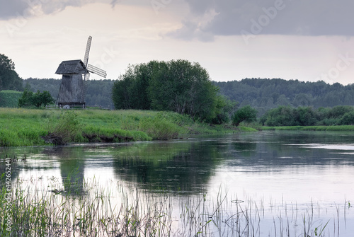 An old traditional Russian windmill on the river bank at sunset in the Pskov region, Russia.