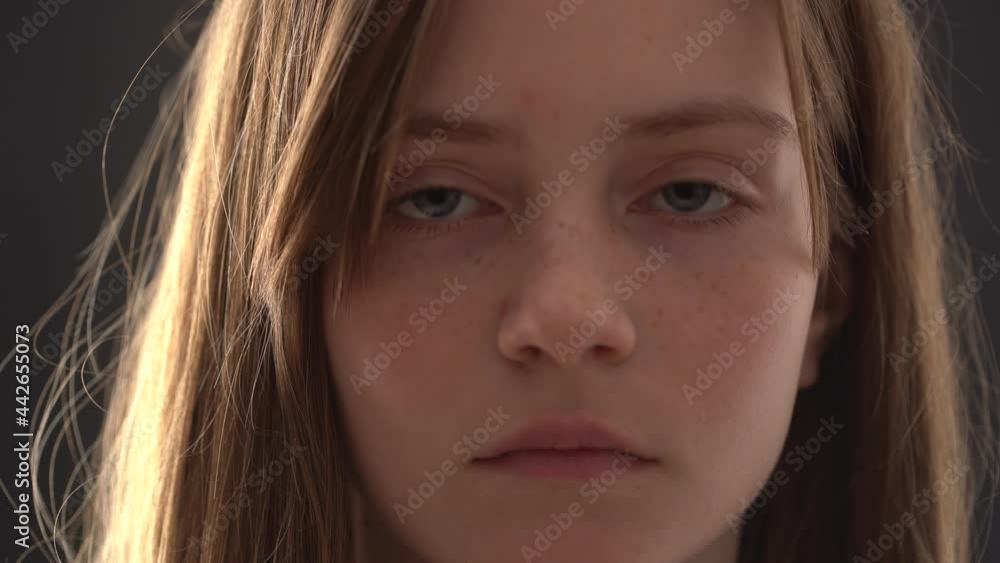Close up of girl face. Charming blond young girl with freckles on a black background, indoors, closeup portrait . Natural beauty Close up of girl face. Charming blond young girl with freckles on a black background, indoors, closeup portrait . Natural beauty