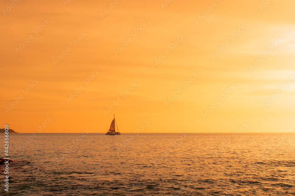 A lone sailboat at sunset. Atmospheric seascape with orange sun. Cloudless sky. The concept of relaxation and relaxation. Idyll.