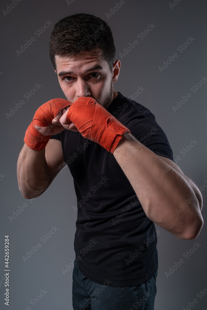 Concentrated fighter with wrist wraps standing in orthodox stance Concentrated fighter with wrist wraps standing in orthodox stance