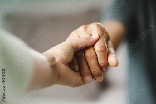 Female friend or family holding hands during cheer up to mental depress man, Psychologist provides mental aid to patient. PTSD Mental health concept