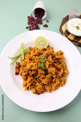 Indian cuisine - Kidney Beans Biryani, Rajma Pulao. Garnished with chopped coriander, and lemon wedges. Rajma biryani served with dahi. Along with copy space. Rajma Chawal flatlay.